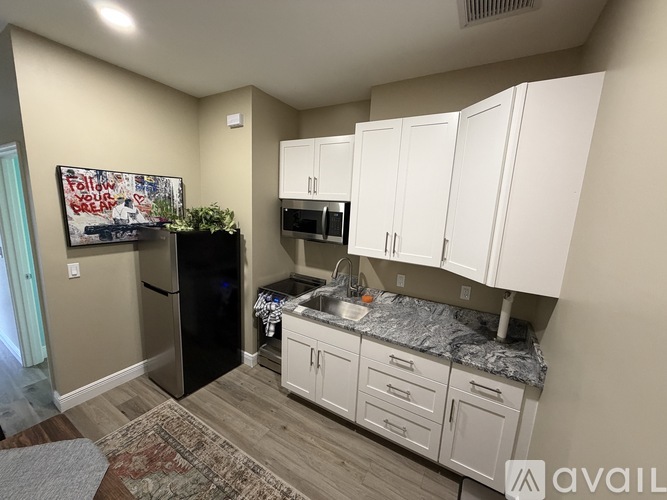 A kitchen with white cabinets and a black fridge.
