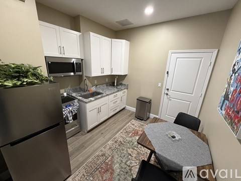 A kitchen with a refrigerator, microwave, and a dining table with chairs.