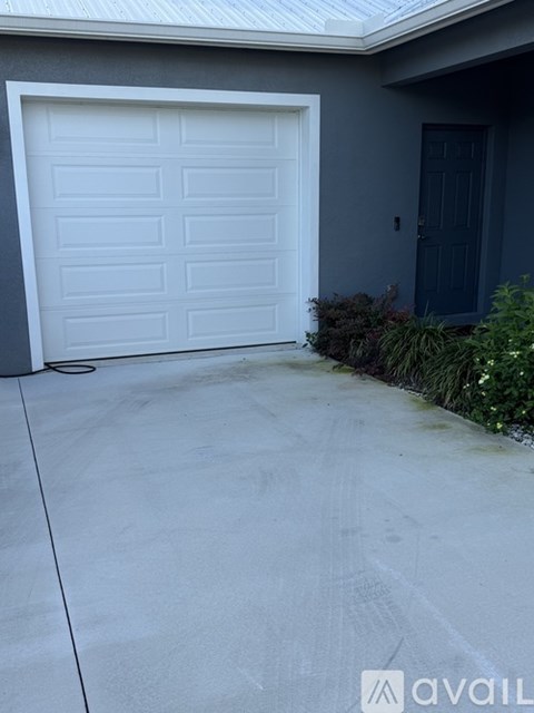 A white garage door is closed and there is a black door to the right of it.