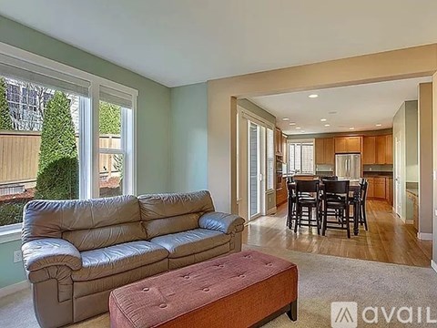 A living room with a grey sofa and a brown ottoman.