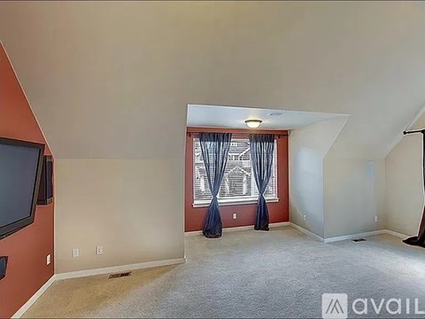 A living room with a television and a window with curtains.