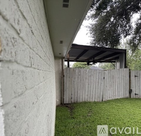 A white wall with a wooden fence and a covered patio area.
