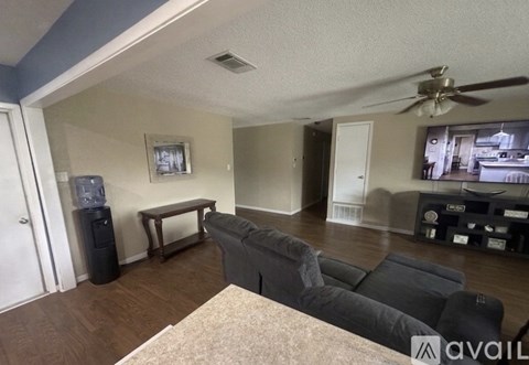 A living room with a grey couch and a fan.