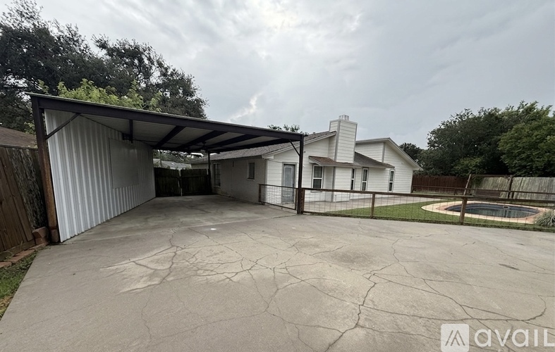 A large, cracked driveway leads to a garage with a metal roof.