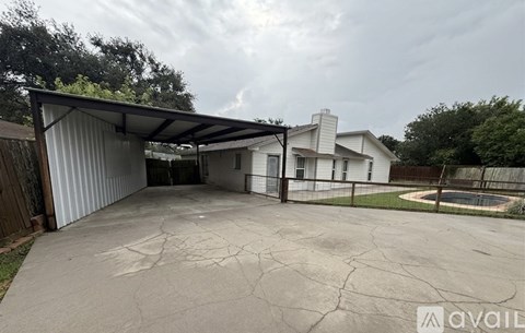 A large, cracked driveway leads to a garage with a metal roof.