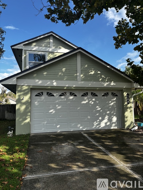 A two-car garage with a white door is attached to a house.