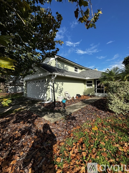 A house with a garage and a driveway surrounded by trees and bushes.