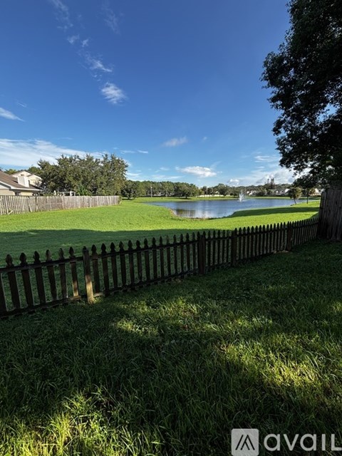 A fenced grassy area with a lake in the distance.