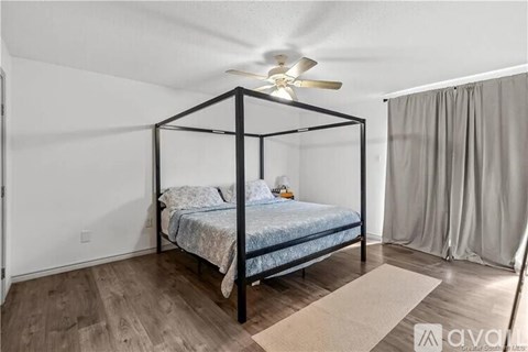 A bedroom with a four-poster bed and a ceiling fan.