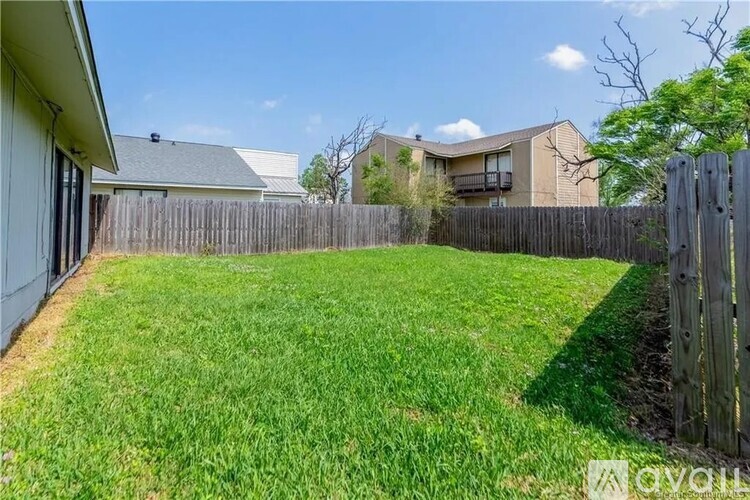 A backyard with a wooden fence and a grassy area.