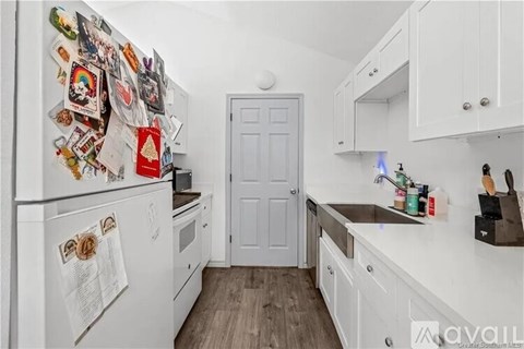 A kitchen with a white fridge covered in magnets and a white door.