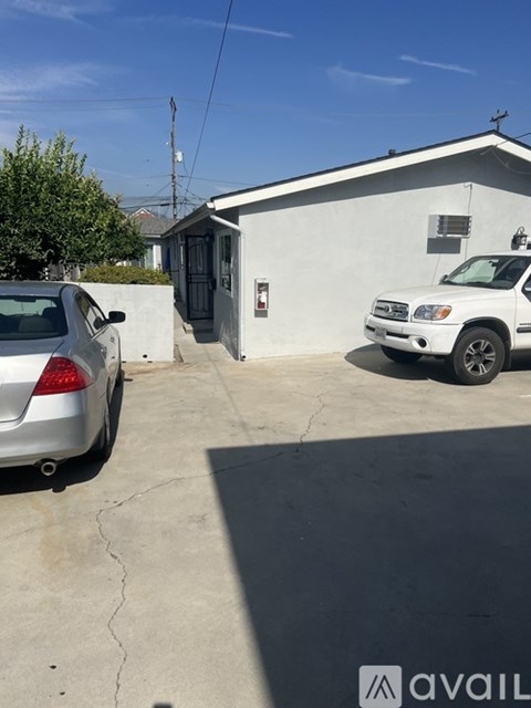 A silver car is parked in a driveway next to a white building.