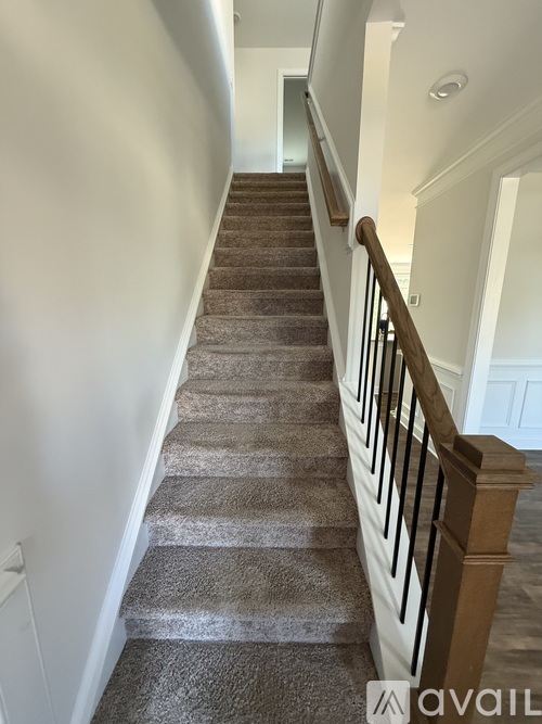 A staircase with a carpeted runner and wooden balusters.
