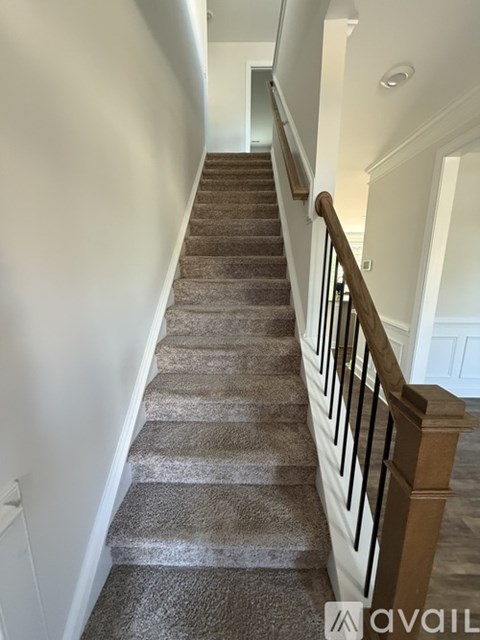 A staircase with a carpeted runner and wooden balusters.