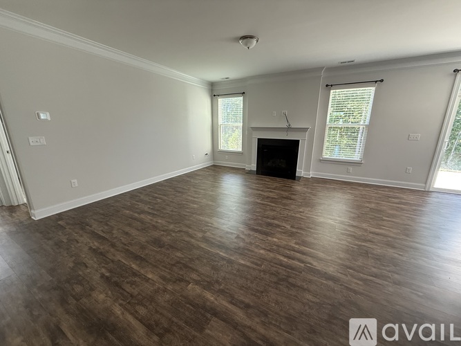 A spacious room with wooden flooring and a fireplace.