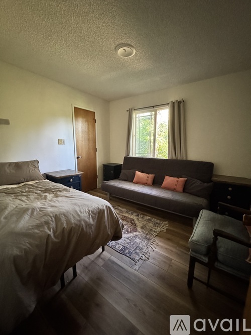 A bedroom with a bed, couch, and chair.