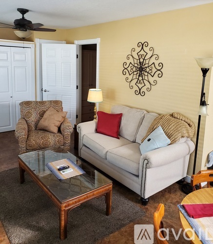 A living room with a white couch, a brown armchair, and a glass coffee table.