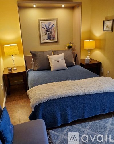 A bedroom with a large bed and two lamps.