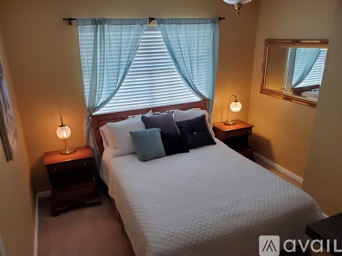 A bedroom with a large bed, two lamps, and a mirror.
