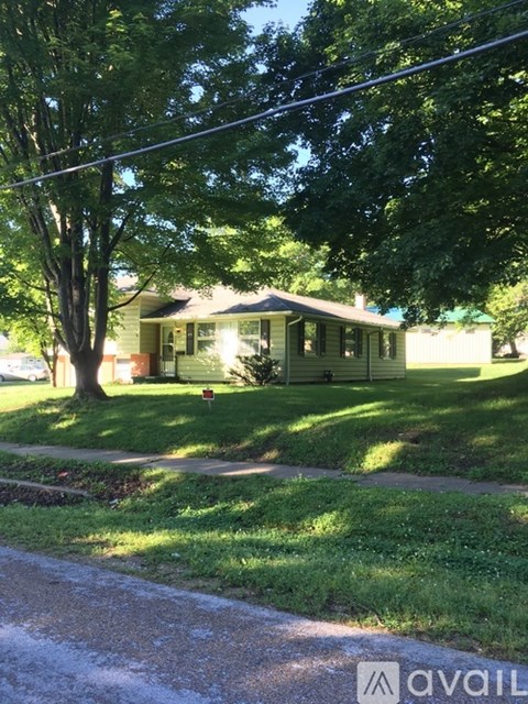 A house with a green lawn and trees in front.