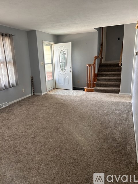 A carpeted room with a staircase leading to another room.