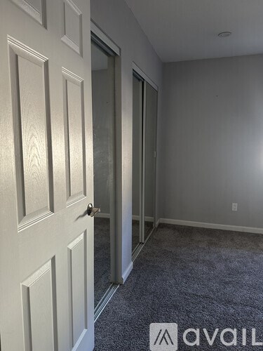 A carpeted hallway with a white door and a glass door leading to another room.