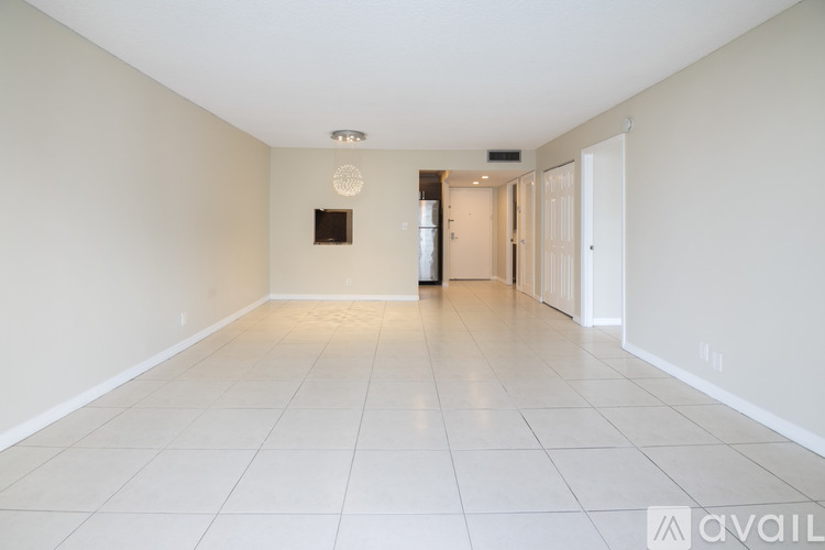 A spacious room with white tiled flooring and white walls.