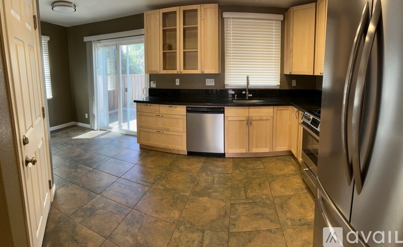 A kitchen with a stainless steel refrigerator and wooden cabinets.