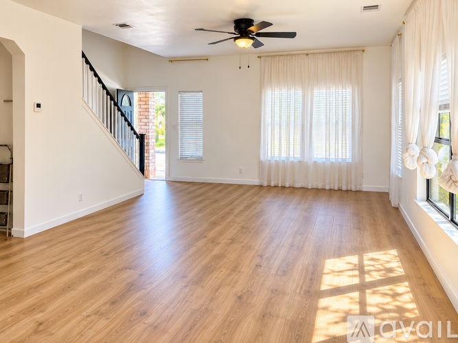 A spacious living room with a staircase and a ceiling fan.