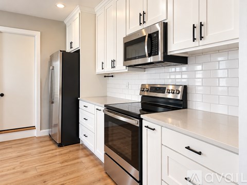 A kitchen with white cabinets and black appliances.