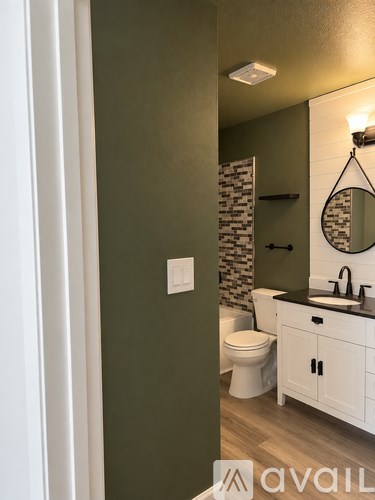 A bathroom with a toilet, sink, and mirror.
