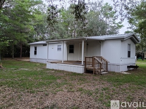 A white mobile home with a porch and a deck.