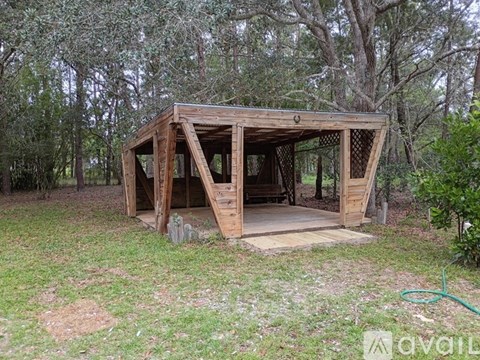 A wooden structure in a grassy area with trees in the background.