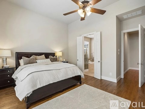A bedroom with a large bed and a ceiling fan.