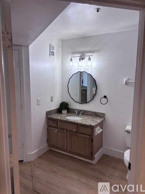 A bathroom with a granite countertop and a round mirror.