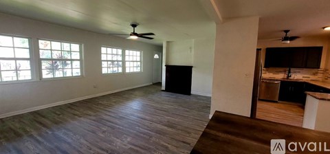 A spacious room with a ceiling fan and large windows.