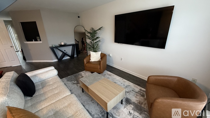 A living room with a couch, chair, and a television mounted on the wall.
