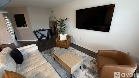 A living room with a couch, chair, and a television mounted on the wall.