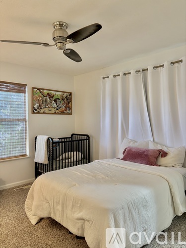 A bedroom with a white bed and a ceiling fan.