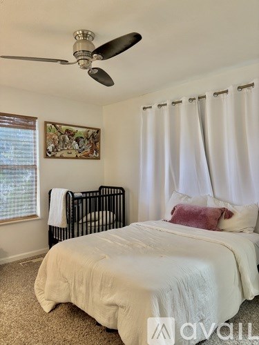 A bedroom with a white bed and a ceiling fan.