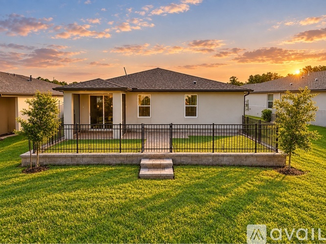 A house with a front yard and a fence is shown in the image.