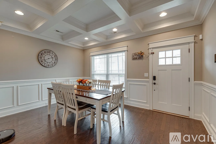 A dining room with a table set for two and a clock on the wall.
