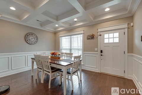 A dining room with a table set for two and a clock on the wall.
