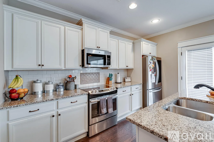 A kitchen with white cabinets and a granite countertop.