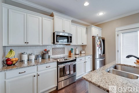 A kitchen with white cabinets and a granite countertop.