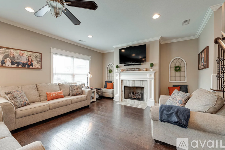 A living room with a fireplace and a television mounted above it.