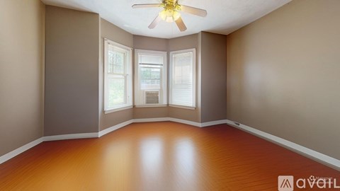 A room with a ceiling fan and wooden flooring.
