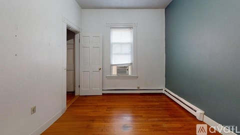 A room with a wooden floor and a window with blinds.