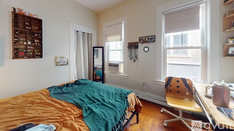 A bedroom with a bed, desk, and chair.