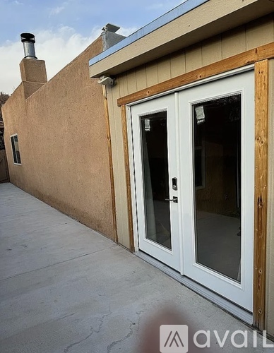 A white door with a glass panel is on the side of a tan building.